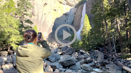 Secretary Haaland snaps a picture of a waterfall at Yosemite National Park. 