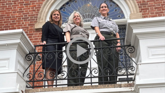 PDAS for Policy, Management and Budget Joan Mooney stands with Park Rangers on a balcony at the Belmont-Paul Women's Equality National Monument.