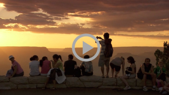 Visitors to Grand Canyon National Park are silhouetted against the sunset.  