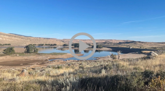 A lake reflects the blue sky in the middle of a sagebrush-covered landscape.