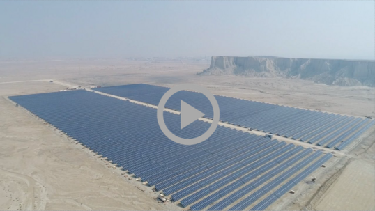 Aerial view of a large solar energy collector in a desert landscape.