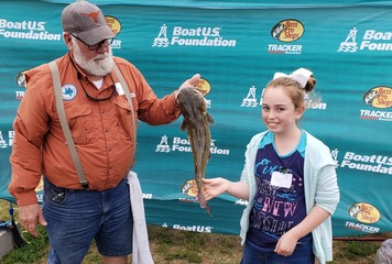 Girl showing her catch at fishing event