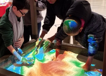 "playing" in an augmented reality sandbox at a youth science day