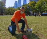 Technician sampling groundwater in park with buildings in background