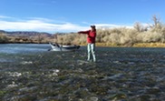 A person stands in shallow water fishing