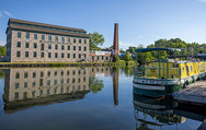 ERCA_Seneca Falls: The former Seneca Knitting Mill reflected in the water with a canal narrow boat in the foreground