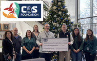 ERCA: A group of office workers stand in front of a Christmas tree with a big donation check