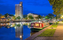 ERCA_Pittsford: A canal narrow boat lit up at night with reflections in the water.