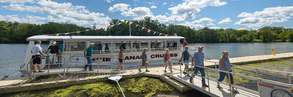 People disembark from a canal tour boat on a sunny day.