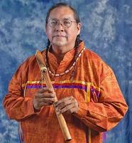 a man in an orange shirt holding a wooden flute