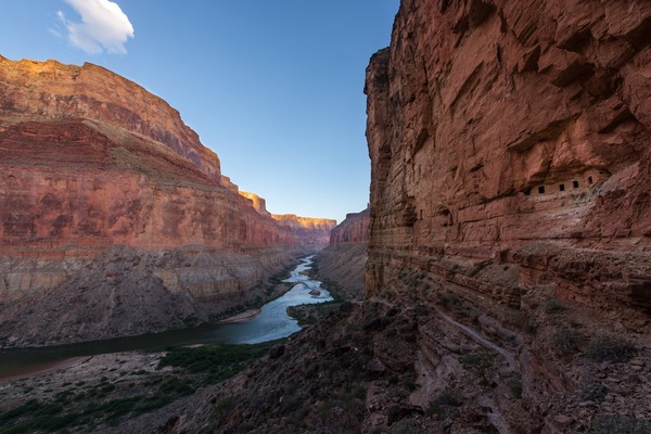 a view looking down a long river between towering desert cliffs