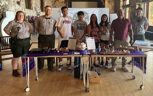 a group of smiling people standing behind a table full of crafts