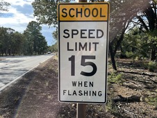 a street sign indicating a school zone with a fifteen mile per hour speed limit