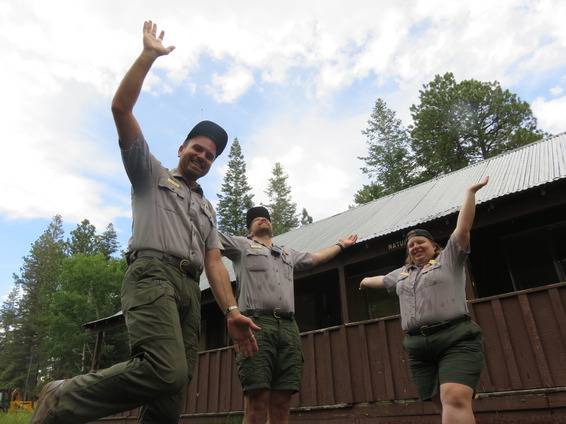 a group of park rangers jumping and smiling in the rain