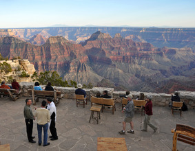 people sitting and walking on a large patio area overlooking the Grand Canyon