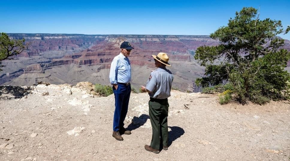 joe biden and a man in a park service uniform talking on the rim of a canyon
