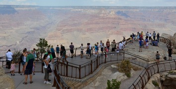 a crowd of people on an overlook at a vast desert canyon