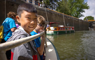 A boy looks over the rail of a boat in a lock during a school field trip to the canal.