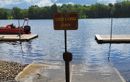 A boat launch with a sign, ramp and docks.