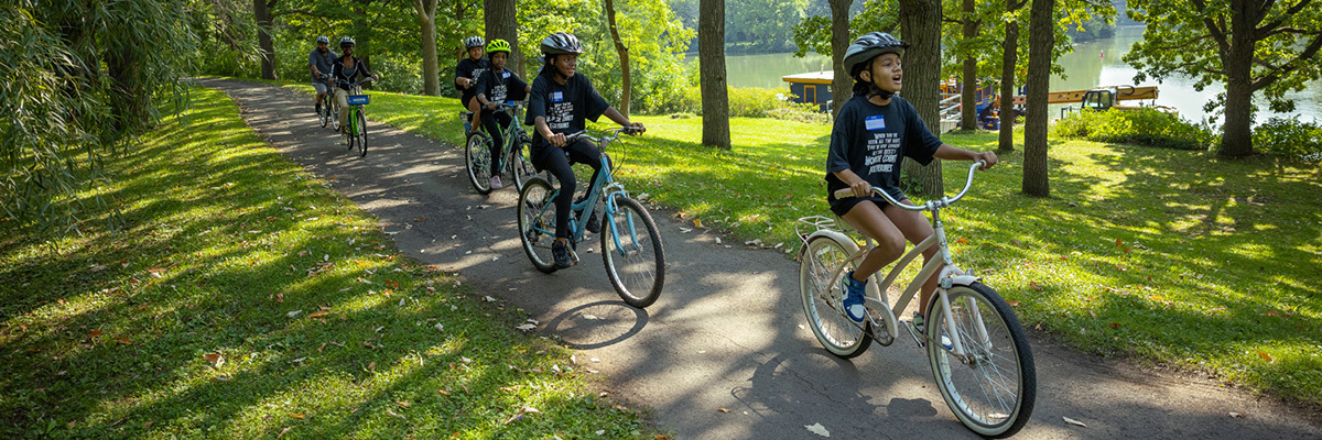 A line of youth riding bikes on the trail with the canal in the backgound.