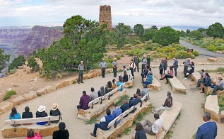 a group of people in an outdoor ampitheater listening to a park ranger speaking