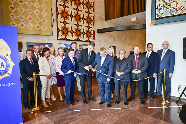 A group of people cut a ribbon, opening a new exhibit. 