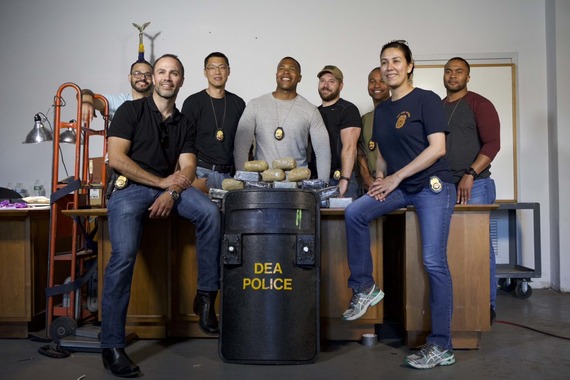 Group of DEA Agents gathered around illicit items