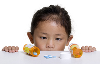child looking at prescription meds on a table