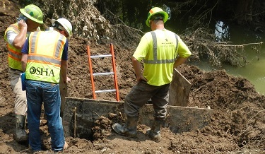 OSHA Compliance Safety and Health Officer Dan Hughes (second from left) speaking with workers in the process of rerouting a water line near Clendenin,