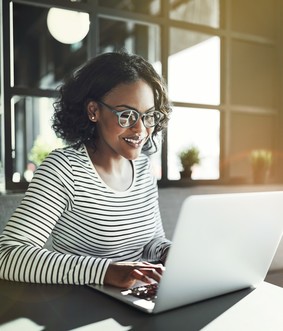 Woman sitting at table typing on laptop