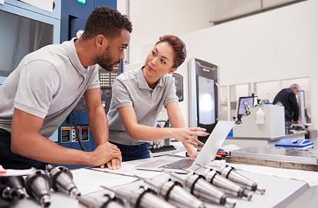 A man and woman discussing work in an industrial setting