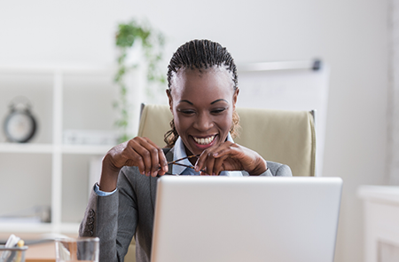 VETS Veteran military spouse - black woman sitting a desk with computer smiling