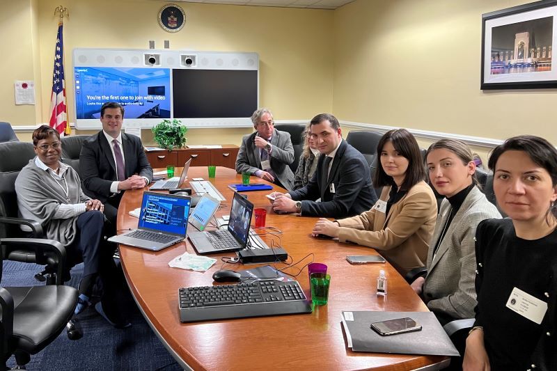 Employees and leaders on the Office of Labor Management Team seated around a dark wood roundtable.