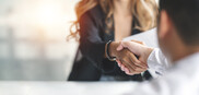 A woman leaning over a table to shake hands with another person