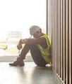 Construction worker sitting alone with head down
