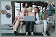 A diverse group of four young adults looking at a laptop together in a modern coworking office setting. One person uses a leg prosthesis.