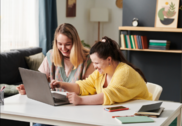 Photo of two people looking at a laptop together. One person has a developmental disability.