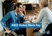 Three people at a table looking over paperwork. One person uses a wheelchair. Text on photo reads, "ABLE Makes Work Pay."