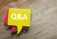 Bird's-eye view of stack of colorful speech bubbles with "Q&A" written on top bubble, on wooden background.