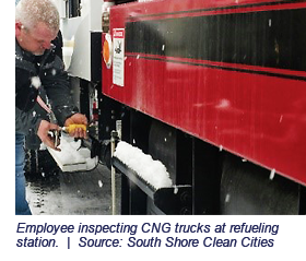 Employee inspecting CNG trucks at refueling station.