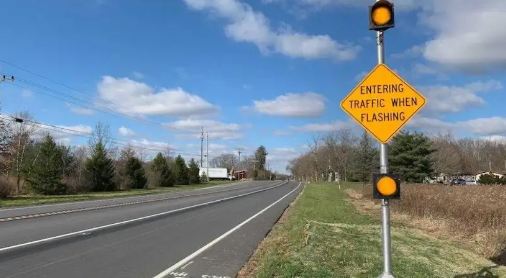 Highway image with intersection conflict warning sign which reads "Entering Traffic When Flashing".