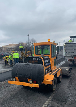 Paving equipment and workers installing asphalt overlay