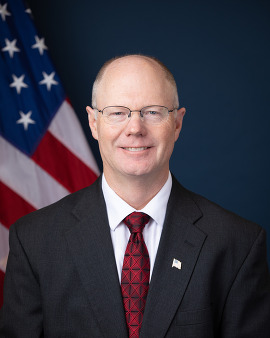 Headshot of Ted Burch, Division Administrator, FHWA MI Division, and NHI Instructor of Excellence, 2023, wearing a black suit and red necktie