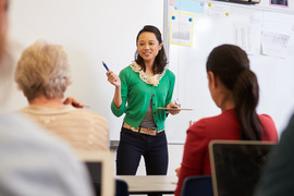 Woman in green cardigan teaching adult learners in front of the training room 