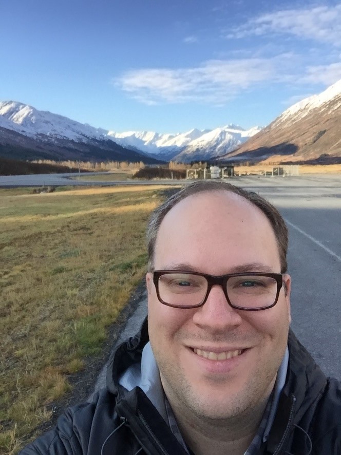 Image of person in front of snow capped mountains. 