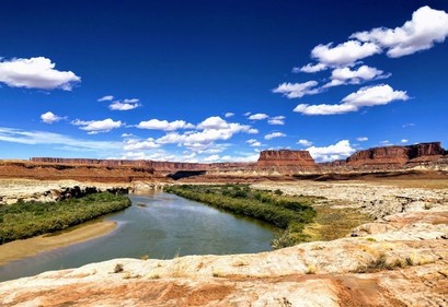 Image from within a canyon with a river flowing in the foreground. 