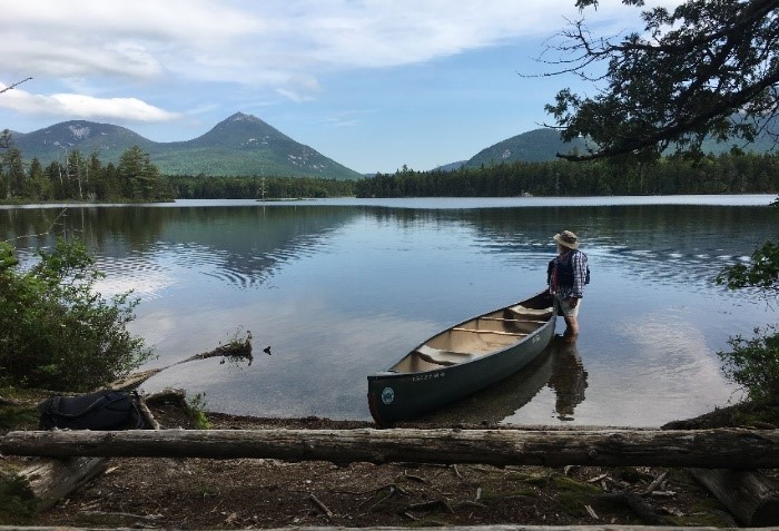 Person sitting in a canoe in a lake with a mountain in the background