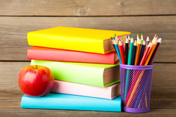 stack of colorful books with an apple and cup full of pencils