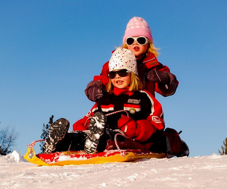 Two young girls riding on a snow sled