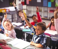 Students raising hands in classroom